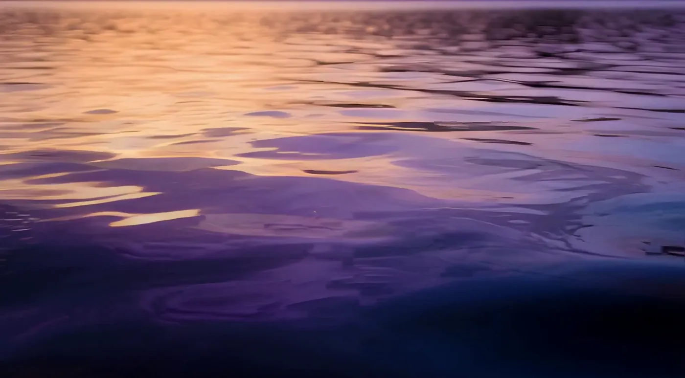 Agua en calma al atardecer, con reflejos violetas y dorados, como una respiración lenta