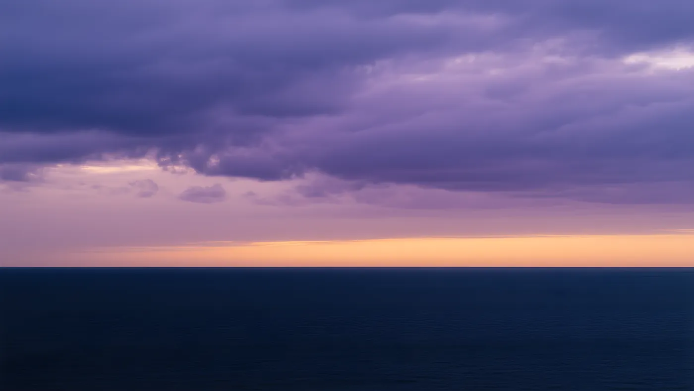 Un cielo malva al atardecer sobre un agua quieta y oscura